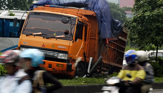 Truk Pengangkut minuman "Nyungsep" di Pembatas Jalan Tol | tempo.co