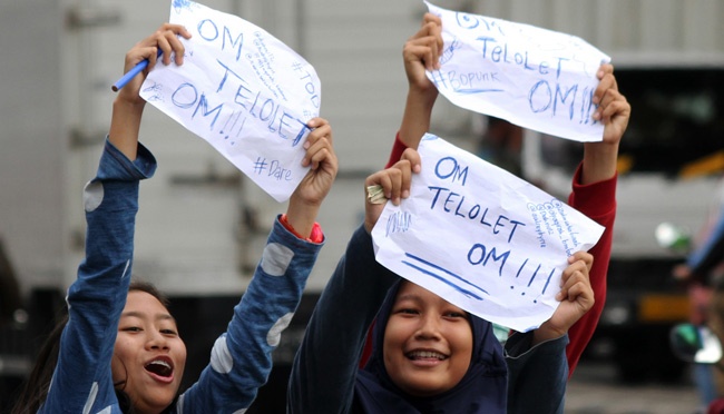 Sejumlah pelajar sekolah menuliskan pesan " Om Telolet Om " agar pengemudi bus membunyikan klakson di Jalan Sudirman, Bekasi, Jawa Barat, 21 Desember 2016. Fenomena " Om Telolet Om " yang menjadi "trending topic" di media sosial. ANTARA/Risky Andrianto