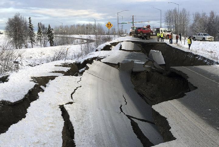 Sebuah truk derek menarik sebuah mobil dari atas jalan raya yang hancur akibat gempa bumi pagi pada Jumat, 30 November 2018, di Anchorage, Alaska. (AP Photo / Mike Dinneen)