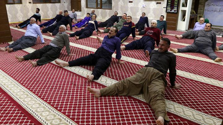 muslim worshipers exercise after the dawn prayer inside a mosque