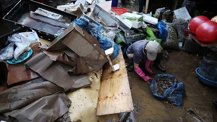 Warga membersihkan puing-puing di pasar tradisional yang rusak akibat banjir setelah hujan deras, di Seoul, Korea Selatan, 9 Agustus 2022.  REUTERS/Kim Hong-Ji