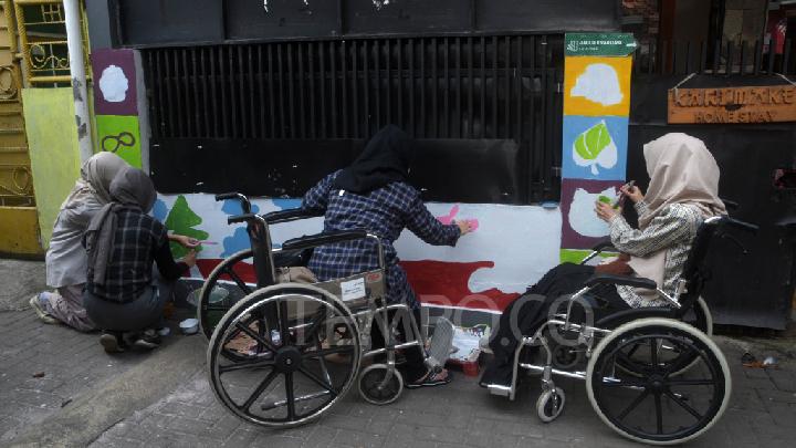 Perempuan penyandang disabilitas melukis mural di kampung rajut Gang Masjid, Kelurahan Binongjati, Bandung, Jawa Barat, 14 Juni 2025.  Tempo/Prima Mulia