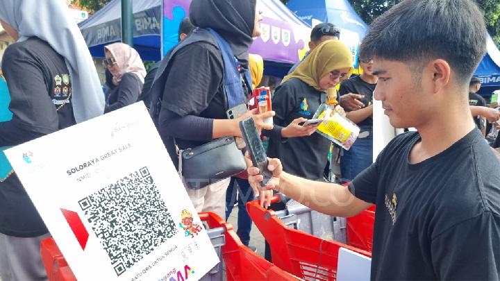 Salah seorang pengunjung melakukan scan kode QRIS untuk pembayaran nontunai produk yang dibeli dengan harga Rp 1 saat pembukaan Solo Raya Great Sale 2025 di Jalan Slamet Riyadi Solo, Minggu, 29 Juni 2025. TEMPO/Septhia Ryanthie
