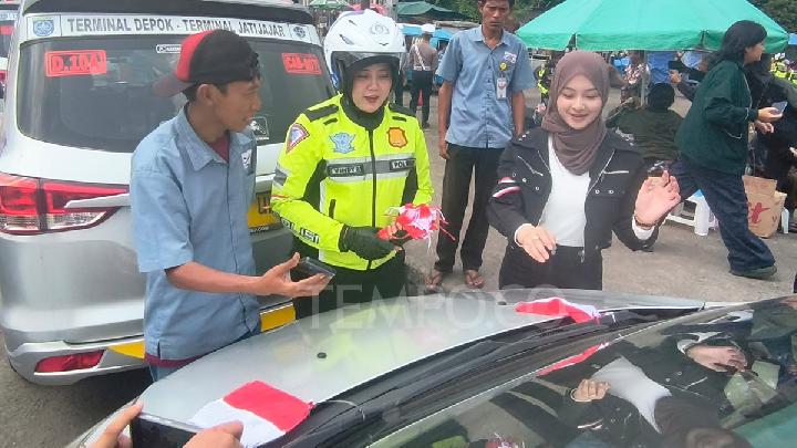Polwan dari Satlantas Polres Metro Depok membagikan dan membantu memasang Bendera Merah Putih di Terminal Depok, Kecamatan Pancoran Mas, Depok, Jawa Barat, 7 Agustus 2025. Tempo/Ricky Juliansyah