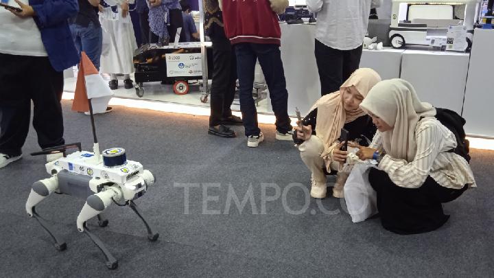 Aksi robot anjing dari ITS menarik perhatian pengunjung pameran Konvensi Sains, Teknologi, dan Industri di gedung Sasana Budaya Ganesha Institut Teknologi Bandung, 8 Agustus 2025. Tempo/Anwar Siswadi